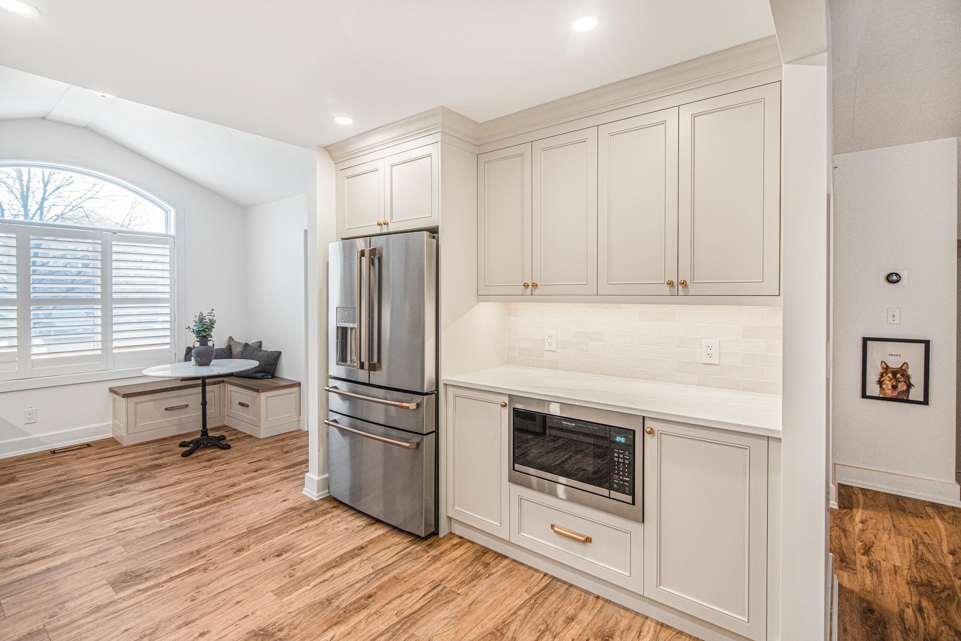 A kitchen with white cabinets , stainless steel appliances , and hardwood floors.