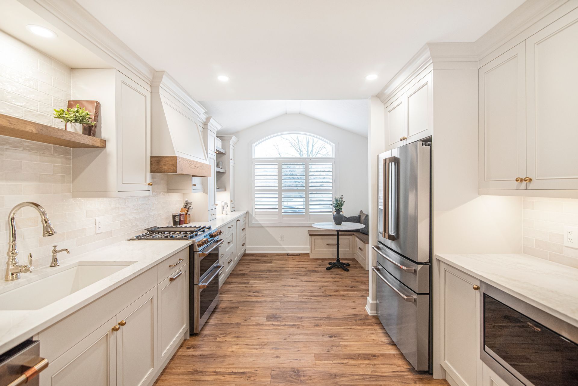 A kitchen with white cabinets , stainless steel appliances , and hardwood floors.