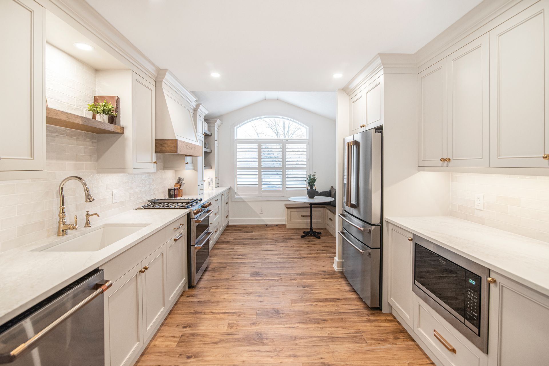 A kitchen with white cabinets , stainless steel appliances , and hardwood floors.