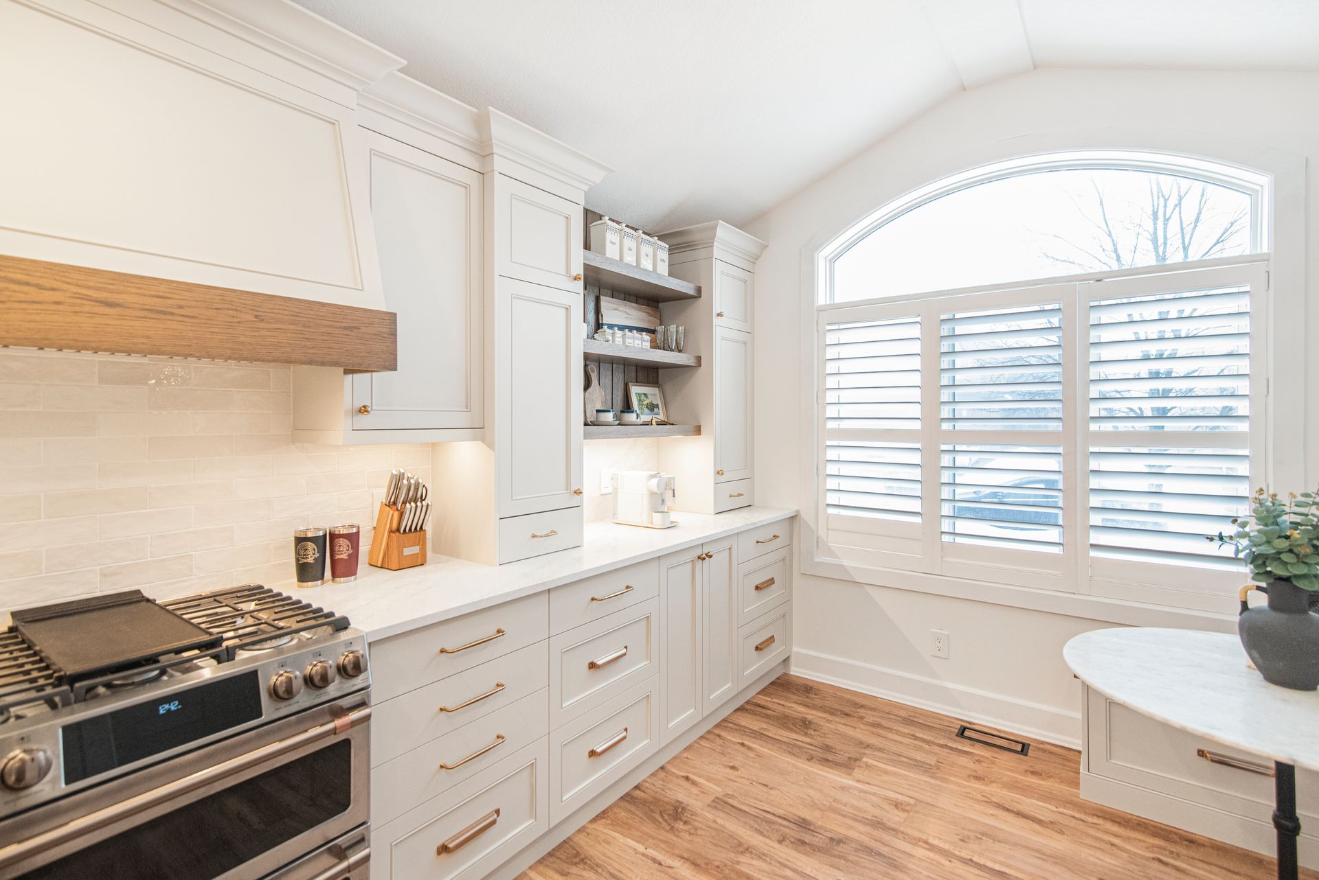 A kitchen with white cabinets and stainless steel appliances and a large window.