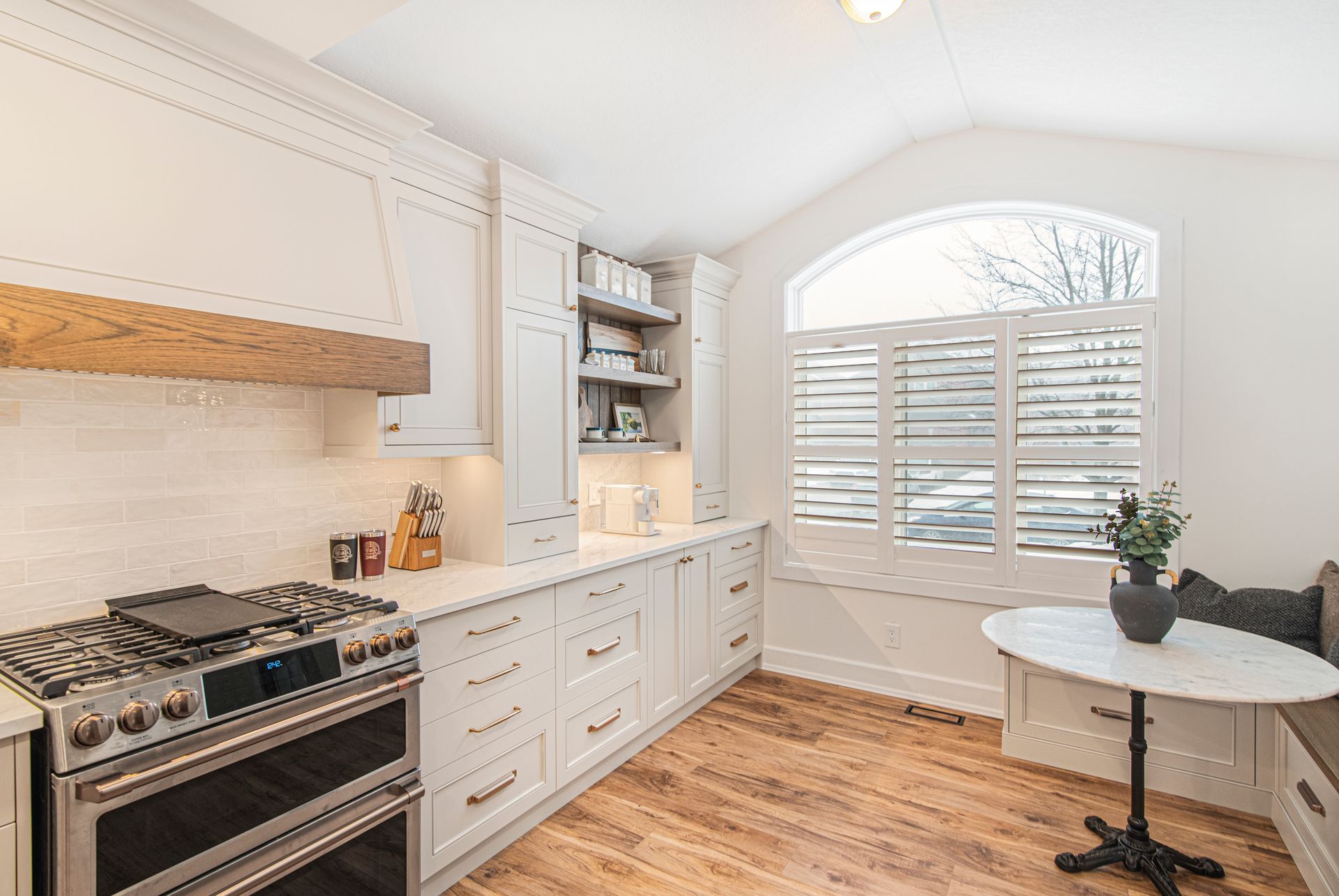 A kitchen with a stove , oven , table and window.