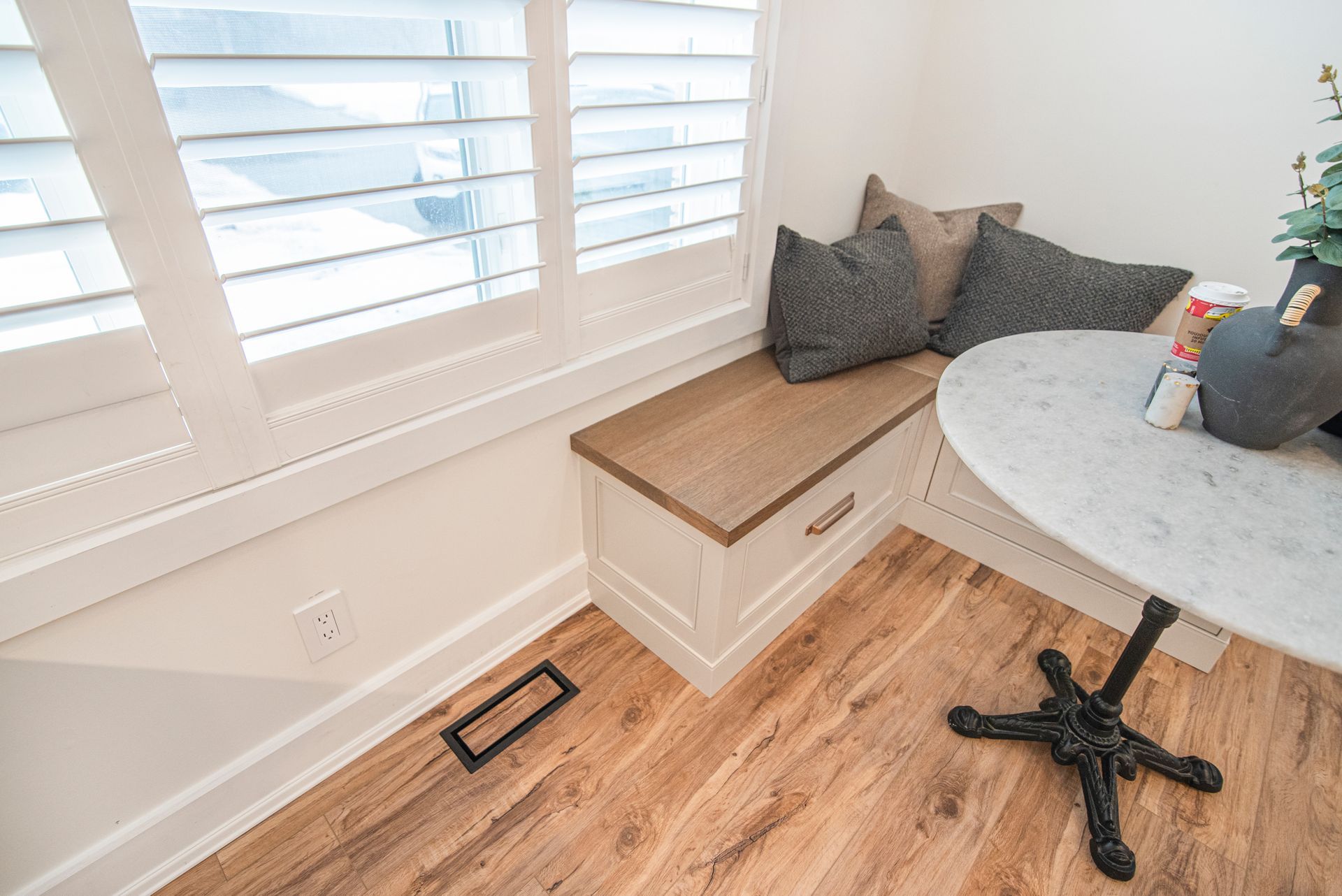 There is a table and a bench in the corner of the room.