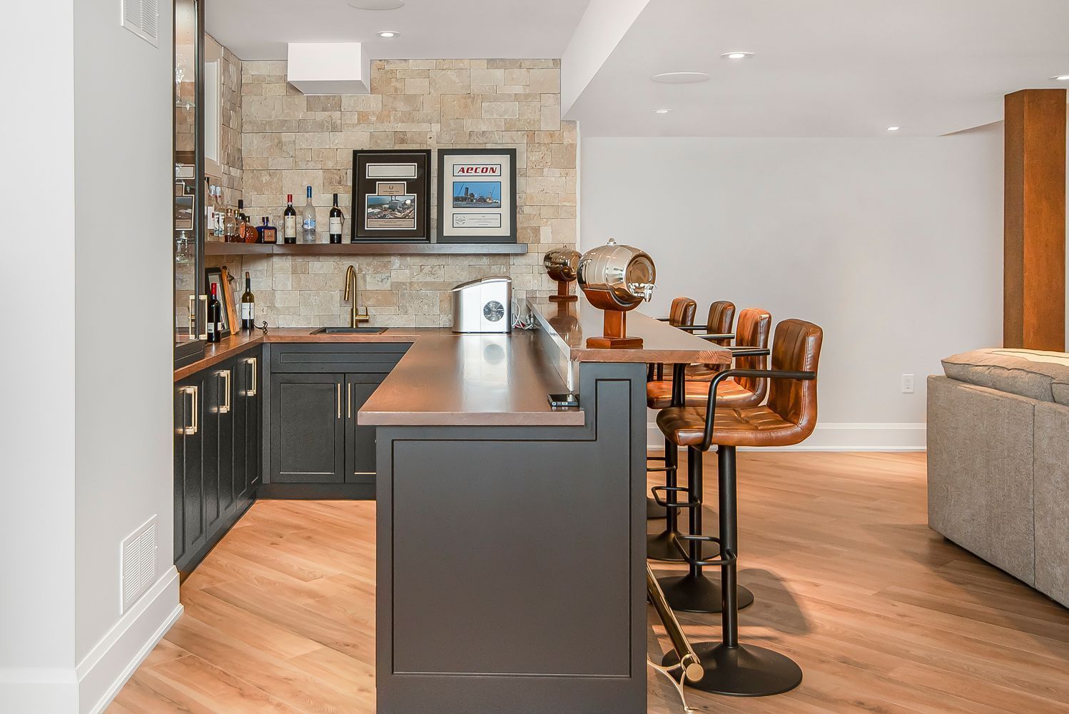 A kitchen with a bar and stools in a basement.