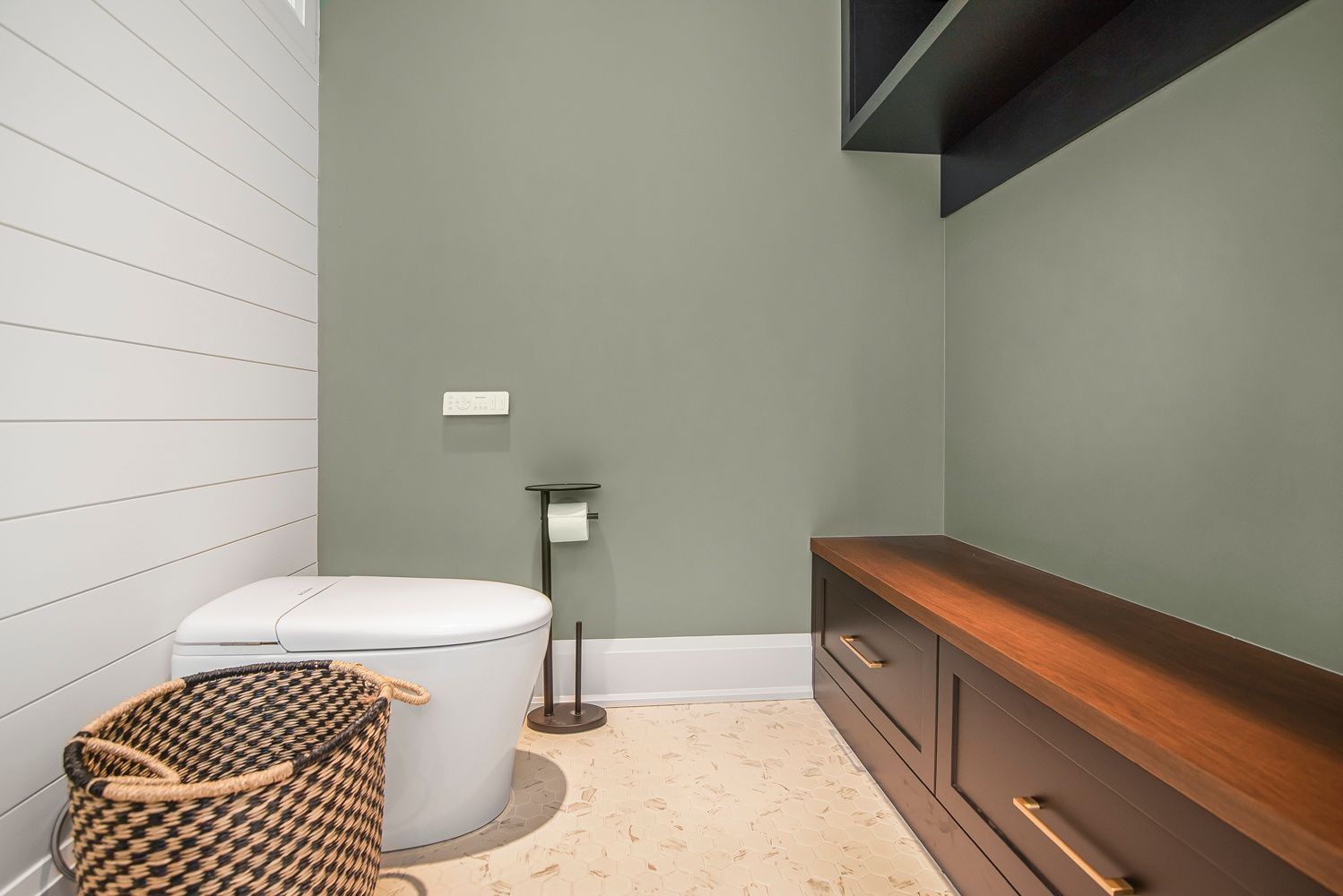 A bathroom with a toilet and a basket on the floor.