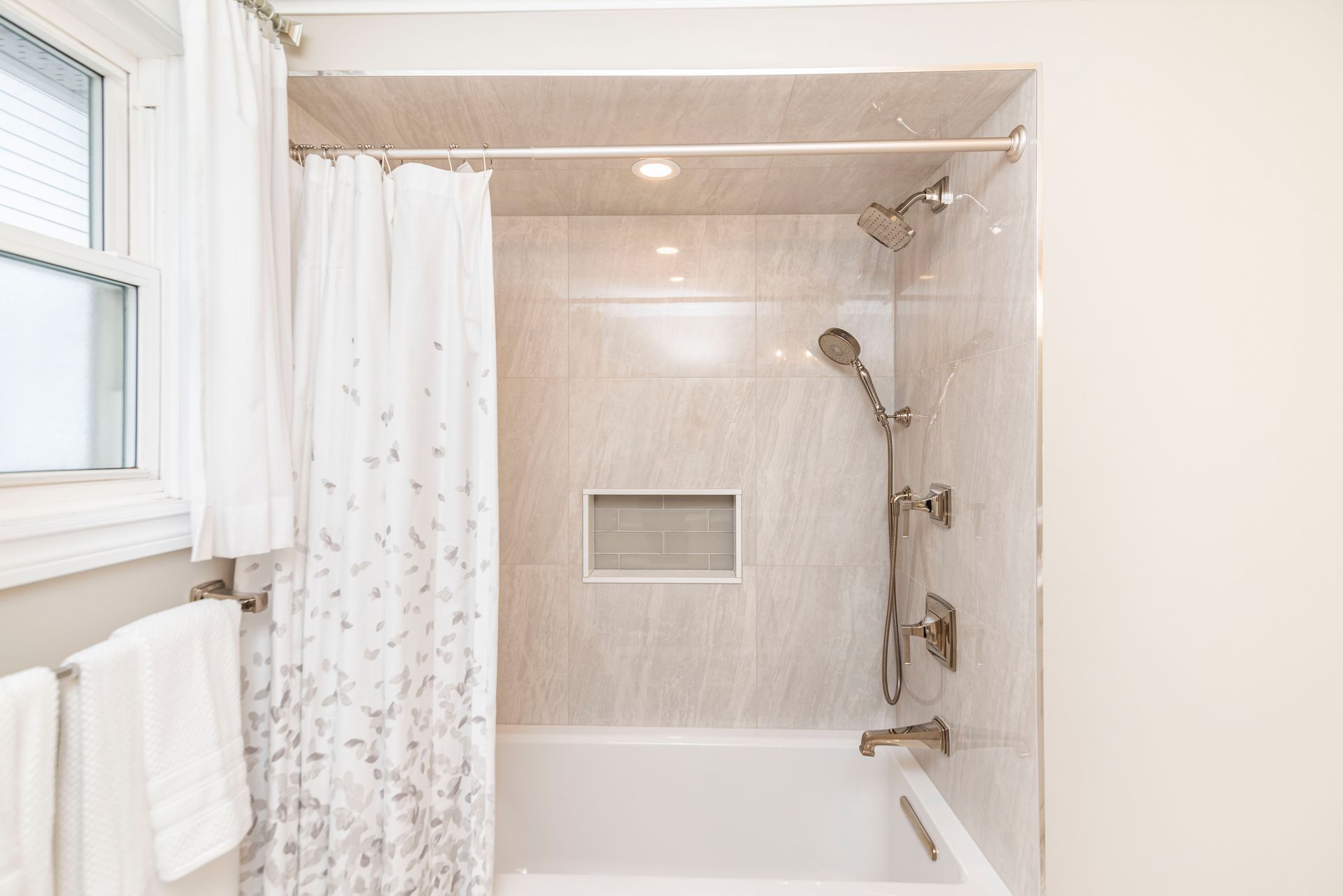 A bathroom with a tub , shower , and window.