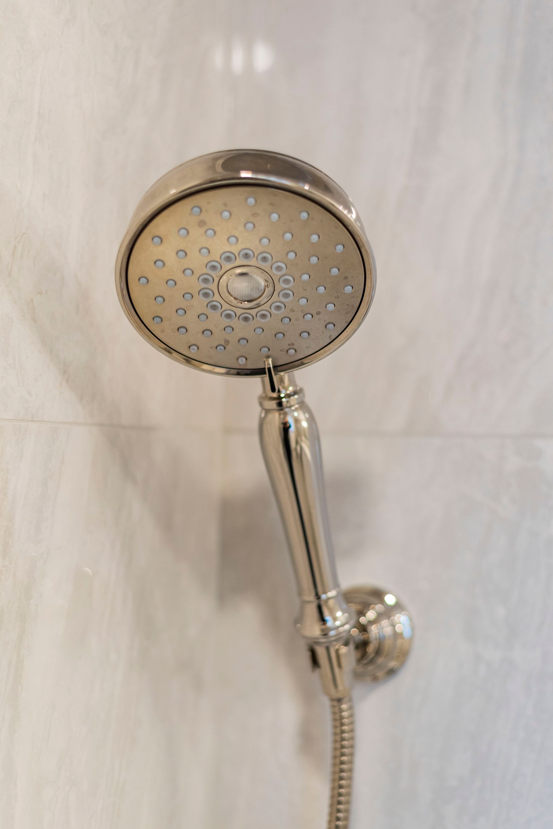 A close up of a shower head with a hose attached to it.