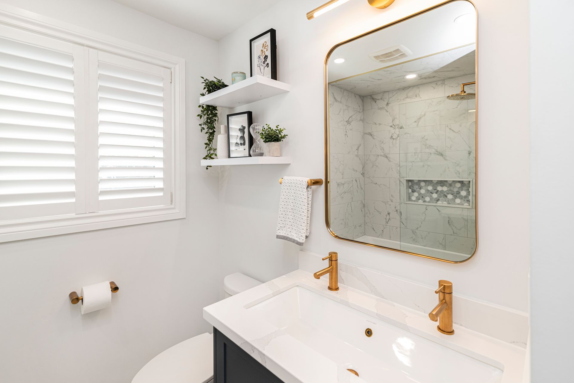 A bathroom with a sink , toilet and gold faucets