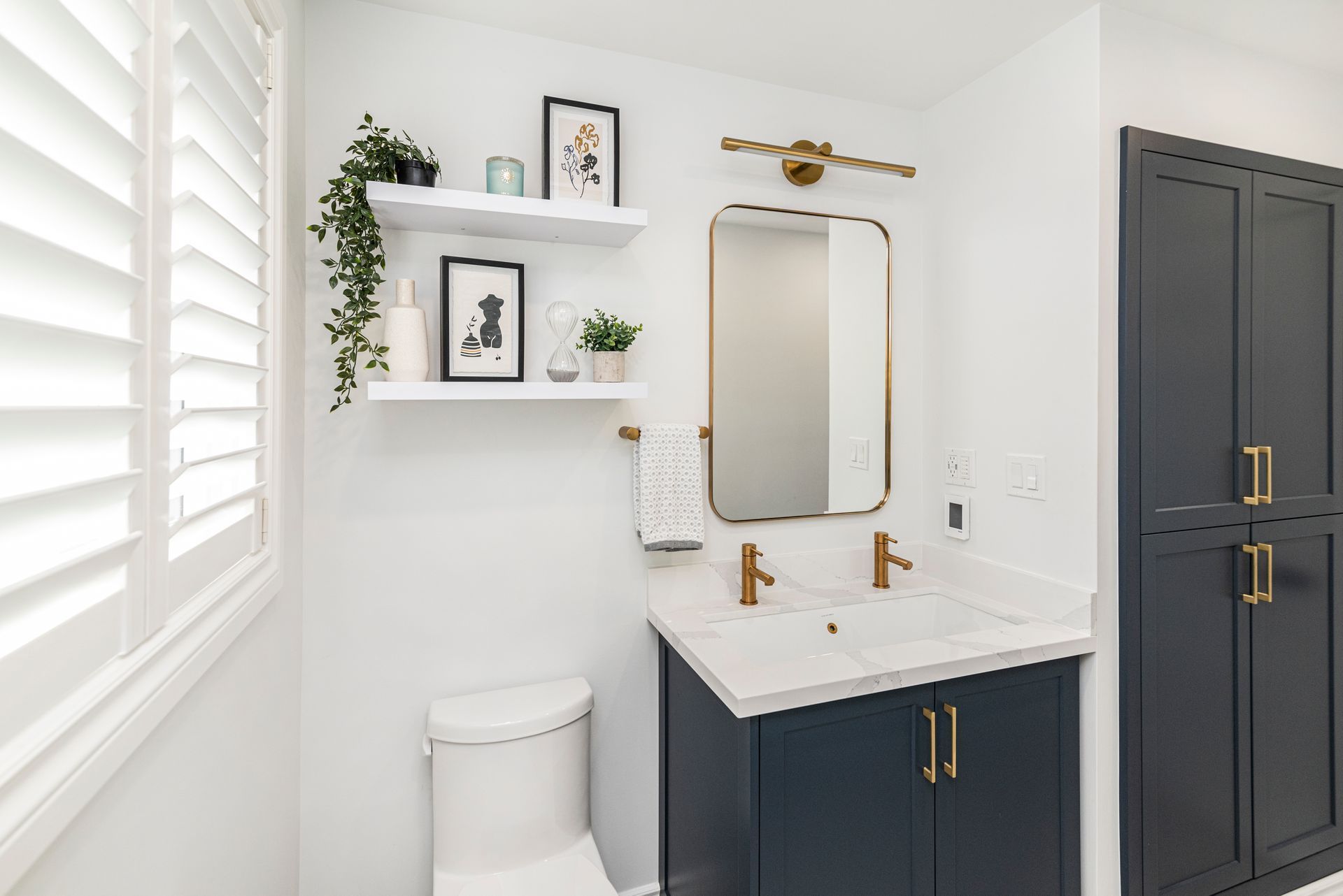 A bathroom with a toilet , sink , mirror and shelves.