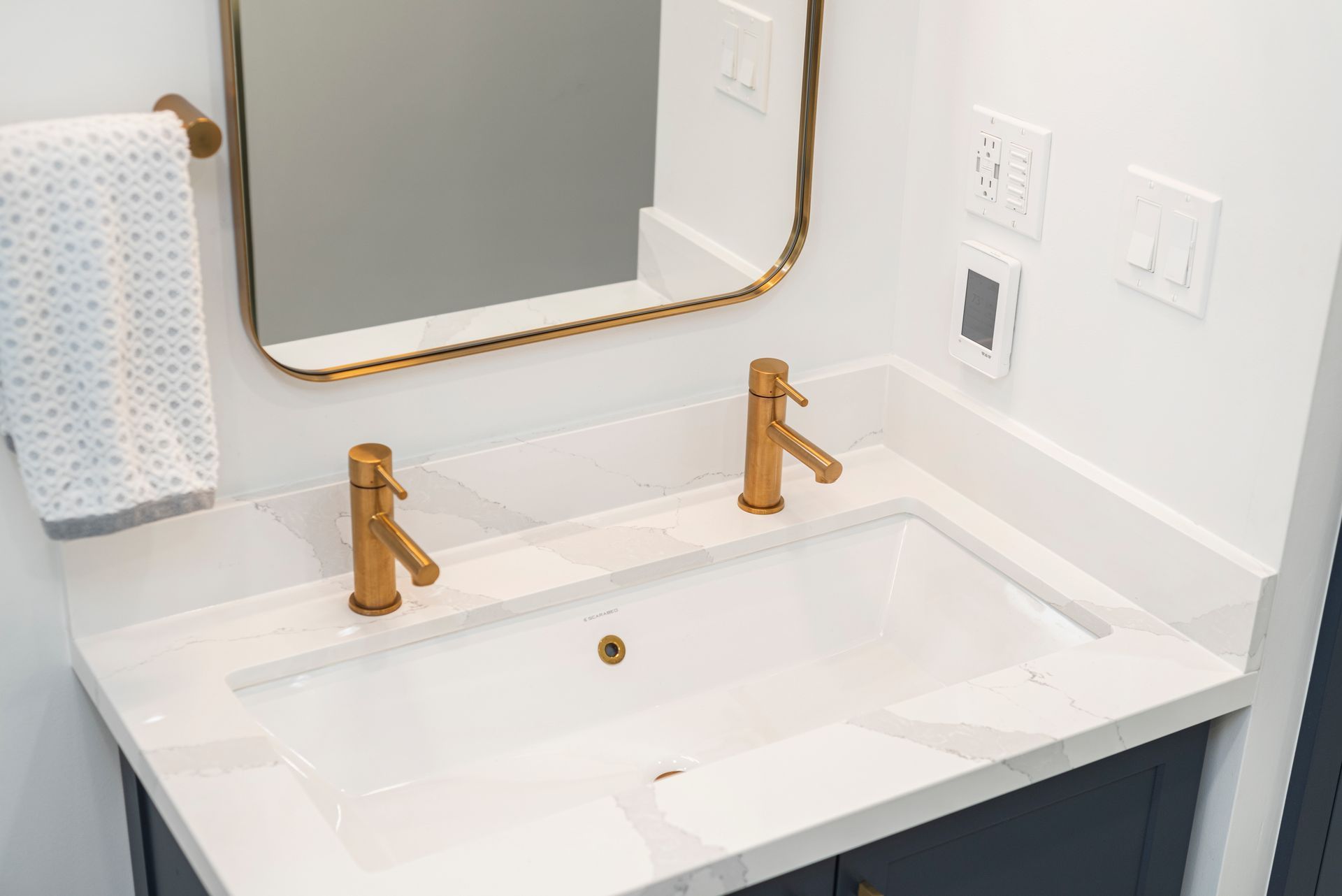 A bathroom sink with two gold faucets and a mirror.