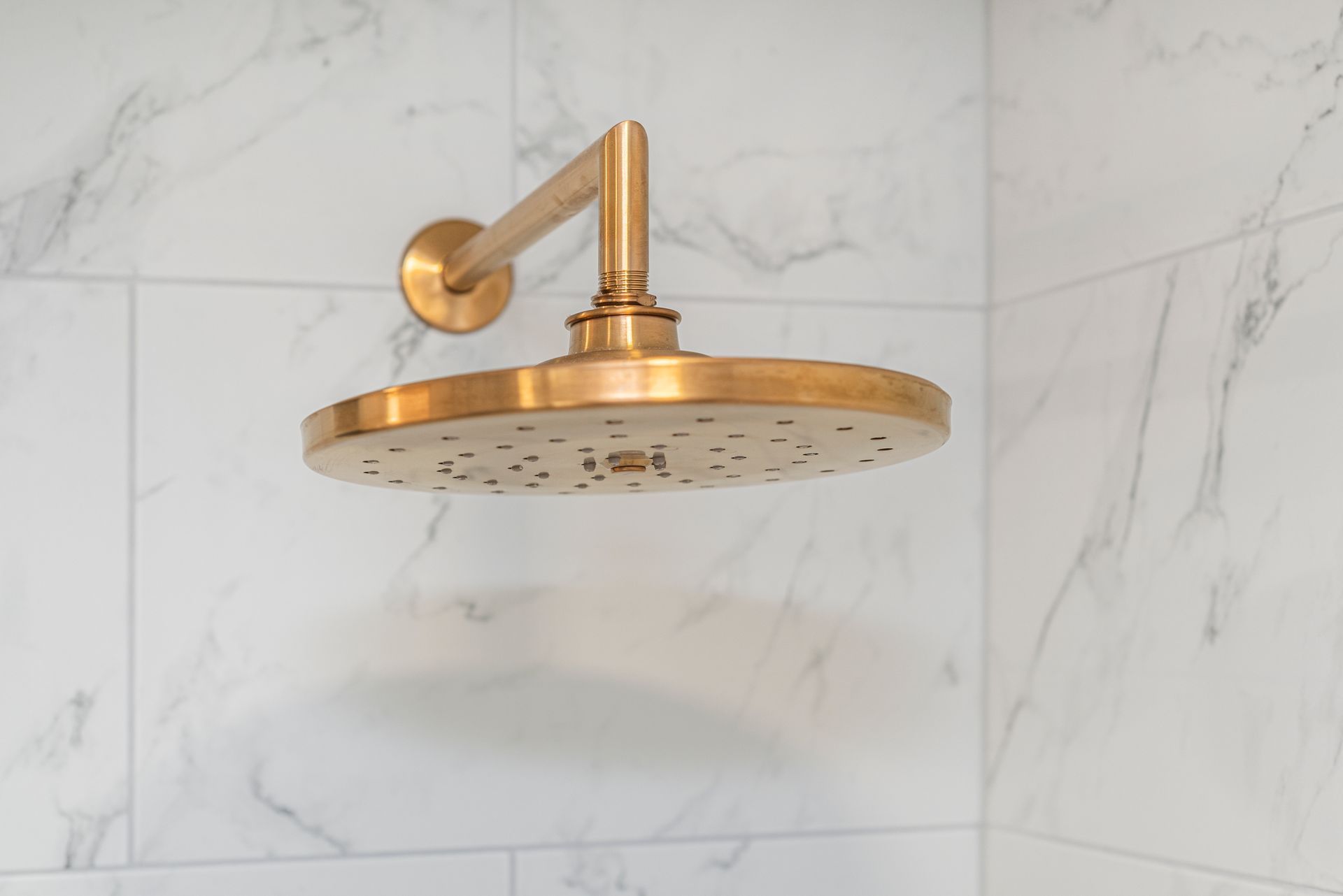 A close up of a brass shower head in a bathroom.