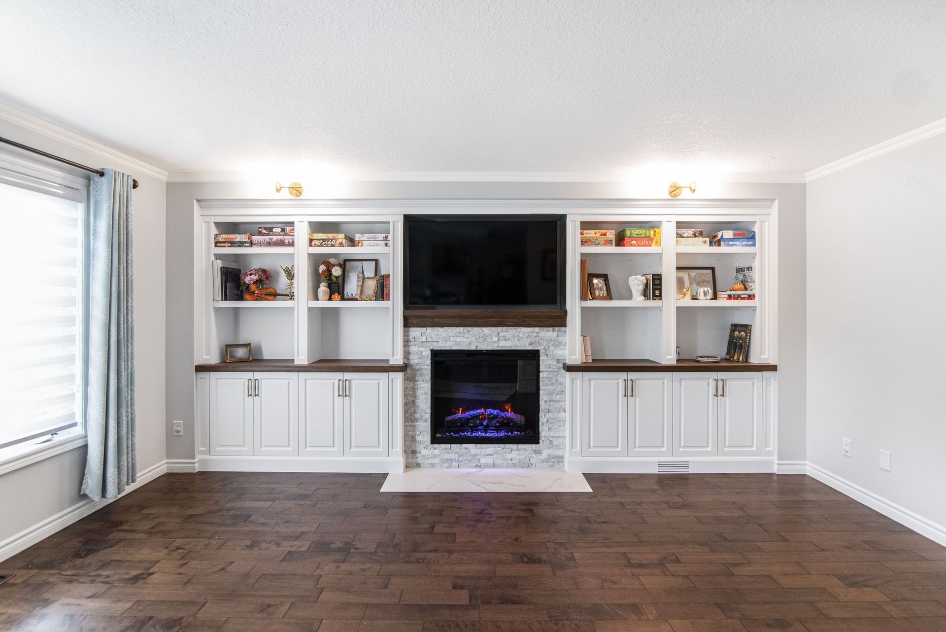 A living room with a fireplace , shelves , and a flat screen television.