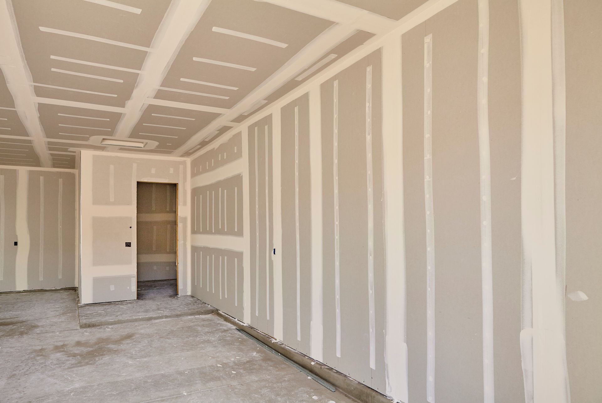 An empty room with drywall on the walls and ceiling.