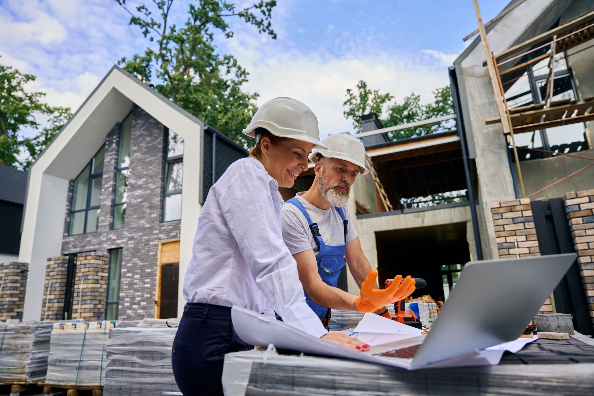 A person installs white vinyl soffit panels along the edge of a house with green horizontal siding.