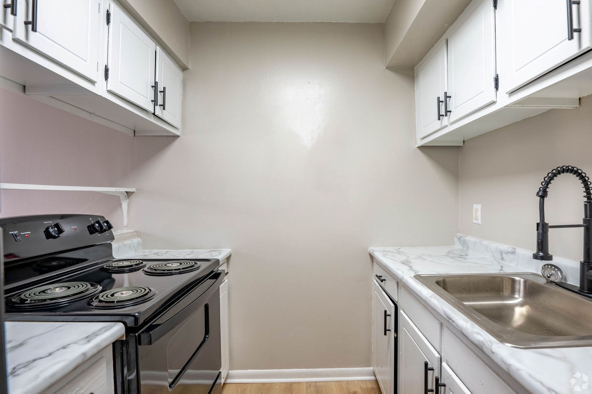 Small kitchen with white cabinets, black stove, and light countertops.