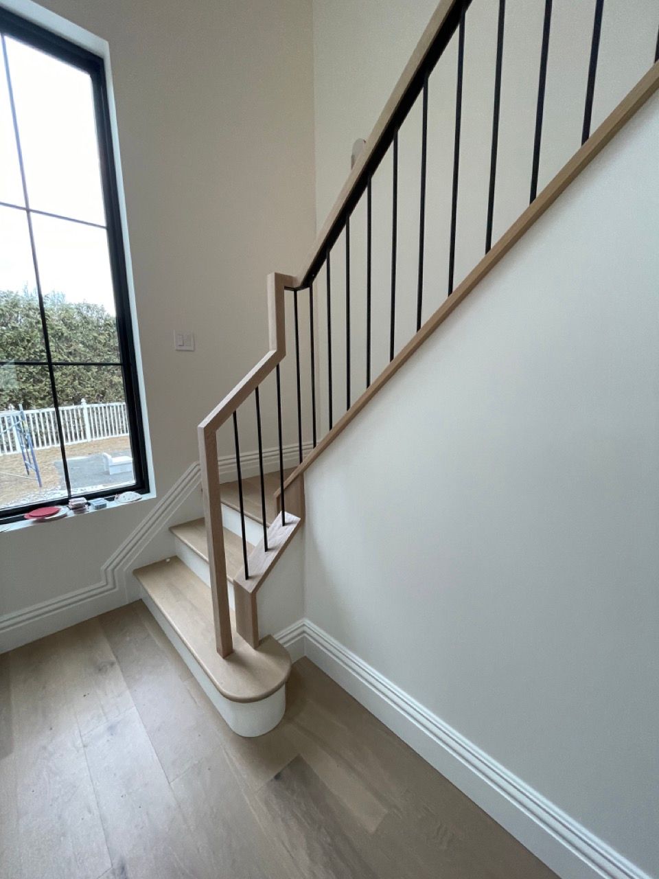 A wooden staircase with a black railing in front of a window