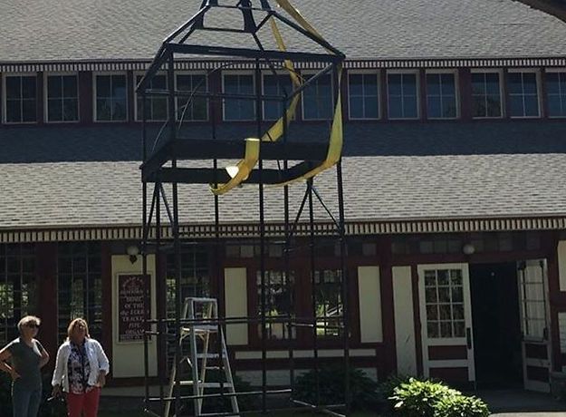 A woman stands in front of a building with a ladder in front of it