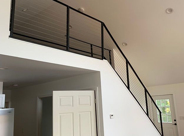 A staircase with a black railing leading up to the second floor of a house.