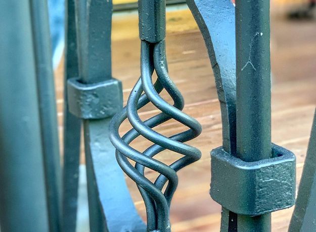 A close up of a wrought iron railing with a spiral design.