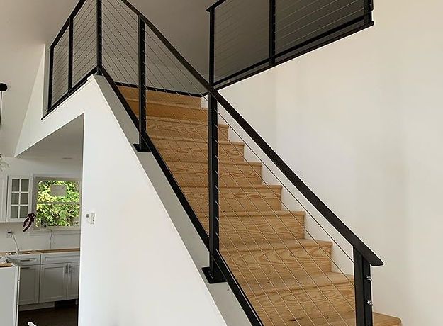 A wooden staircase with a black railing in a house.