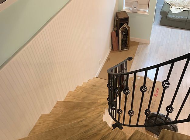 A wooden staircase with a wrought iron railing in a living room.