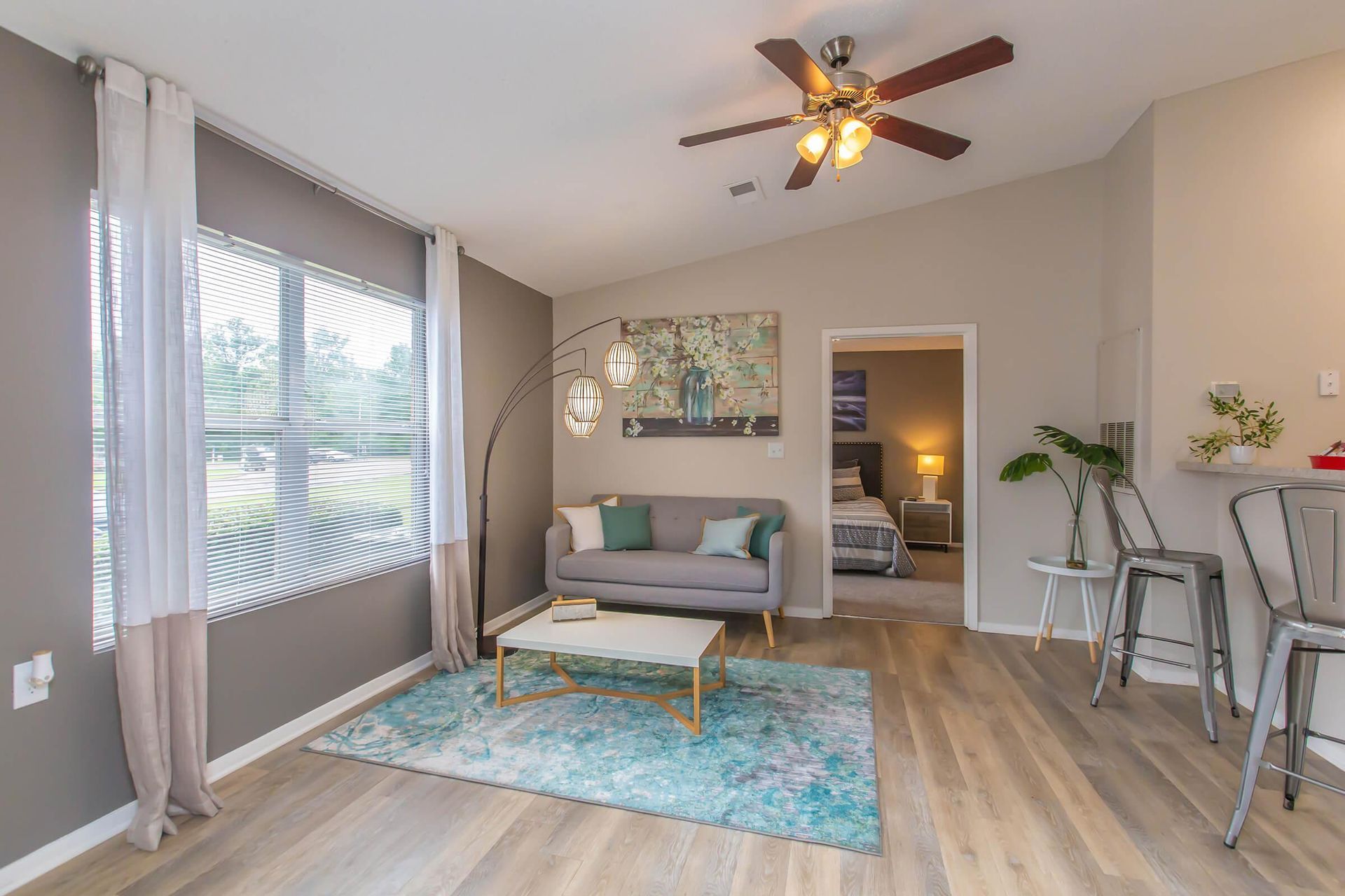 A living room with a couch, coffee table, chairs, and a ceiling fan at 51 at Southaven Apartment Homes in Southaven, MS.
