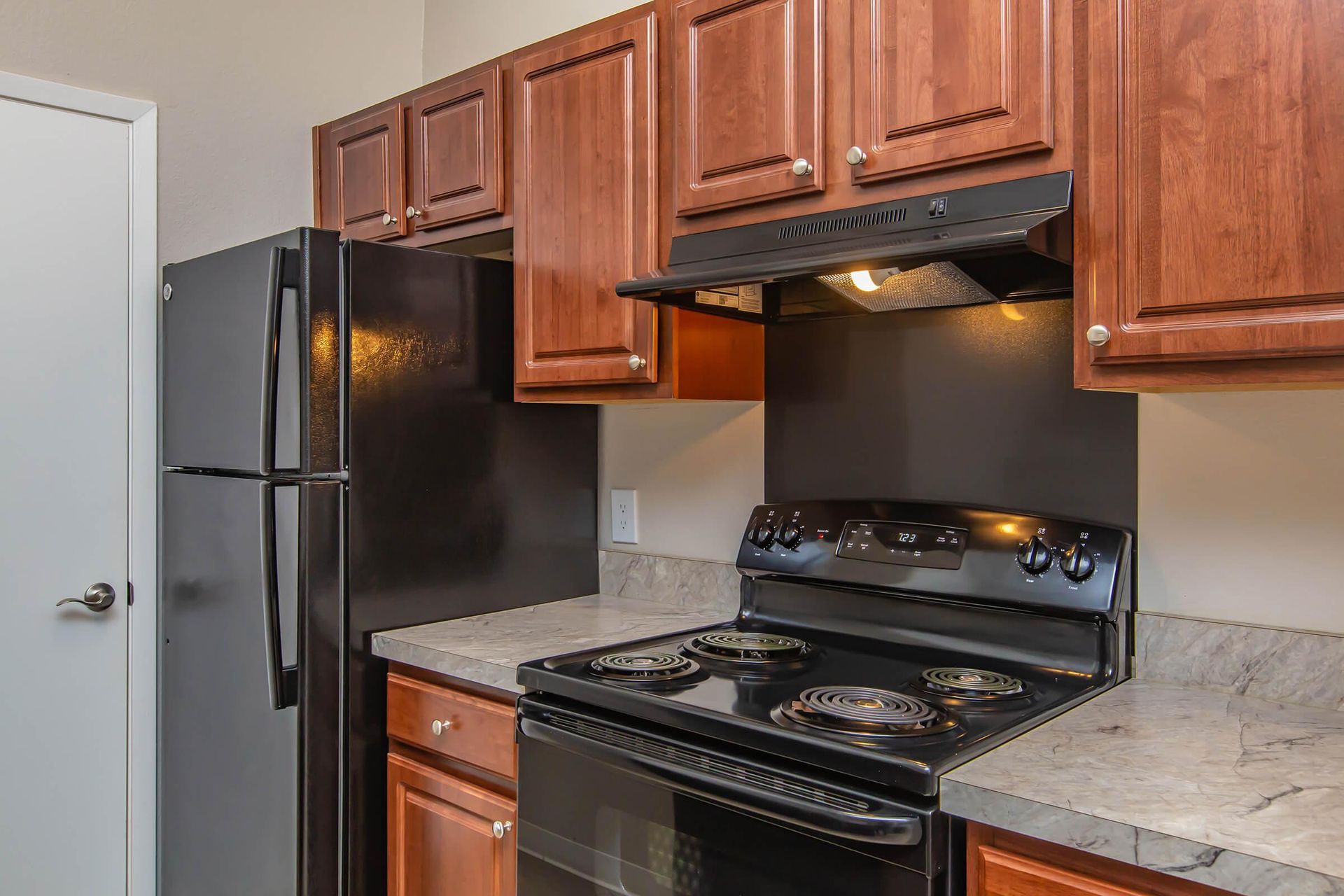 A kitchen with a stove, refrigerator, and wooden cabinets at 51 at Southaven Apartment Homes in Southaven, MS.