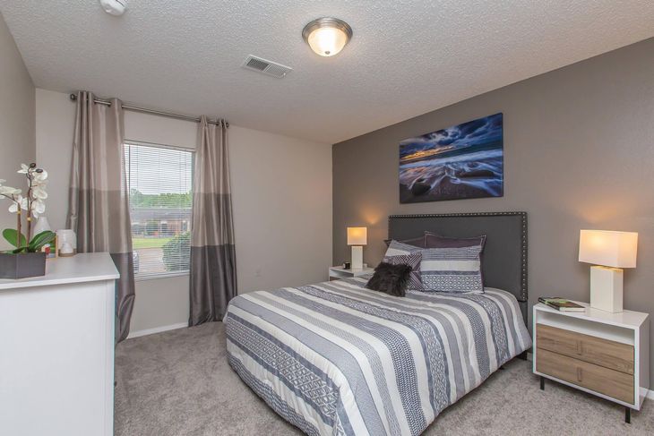 Bedroom with bed, bedside tables, art, window, and dresser. Gray walls, striped bedding, and carpet.