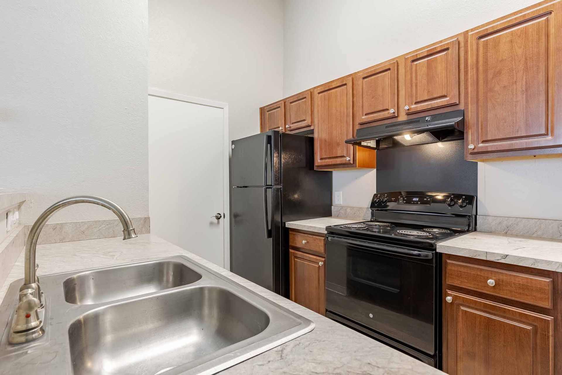 A kitchen with a stove, refrigerator, and wooden cabinets at 51 at Southaven Apartment Homes in Southaven, MS.