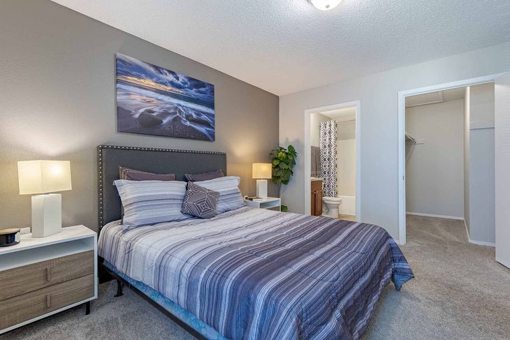 Bedroom with bed, bedside tables, art, window, and dresser. Gray walls, striped bedding, and carpet.
