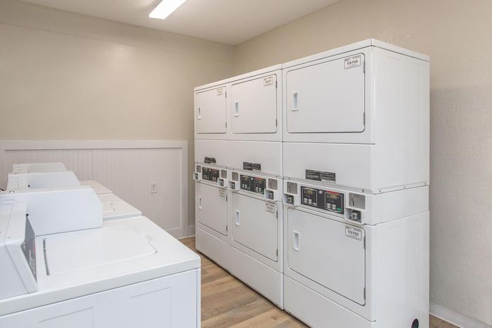 Laundry room with multiple white washers and dryers.