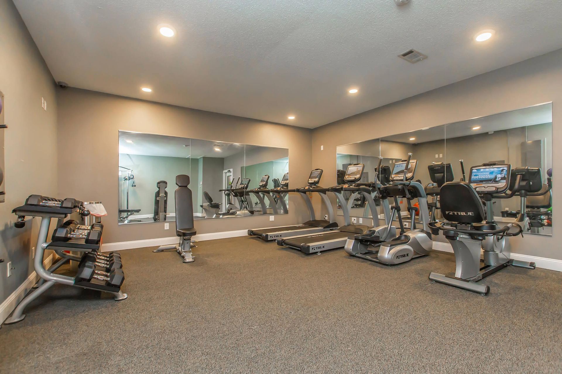 A gym with a lot of equipment and a lot of mirrors at 51 at Southaven Apartment Homes in Southaven, MS.