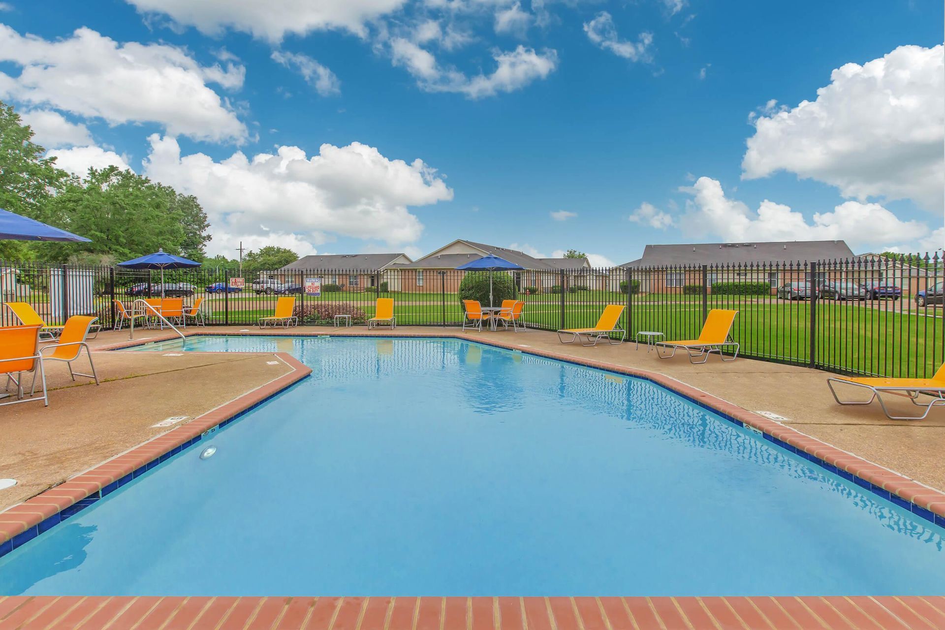 A large swimming pool surrounded by chairs and umbrellas at 51 at Southaven Apartment Homes in Southaven, MS.