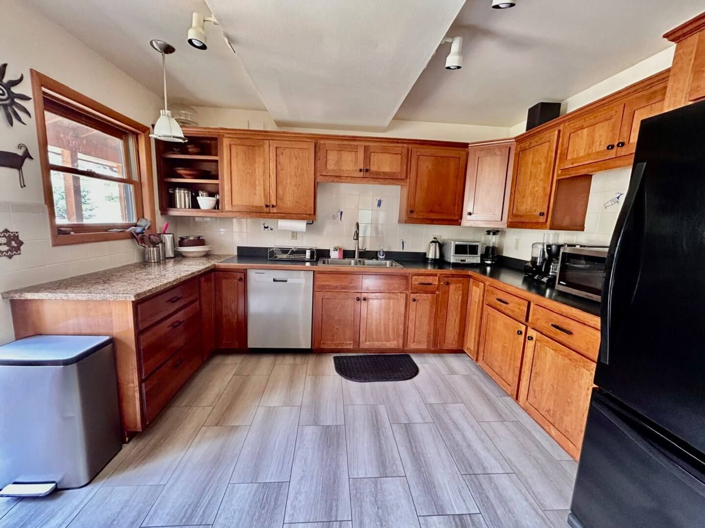 Kitchen with light wood cabinets, gray countertops, stainless steel appliances, and gray flooring.