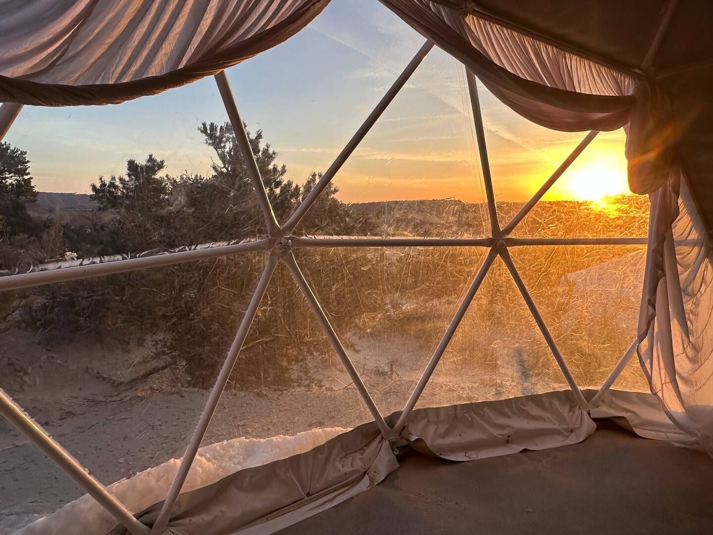 Inside a geodesic dome, sunset over snowy landscape through the clear panels.