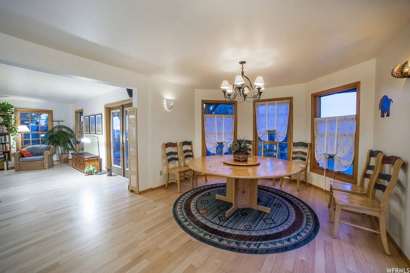 Spacious dining area with round table, chairs, and large windows. Light wood floors and soft lighting.
