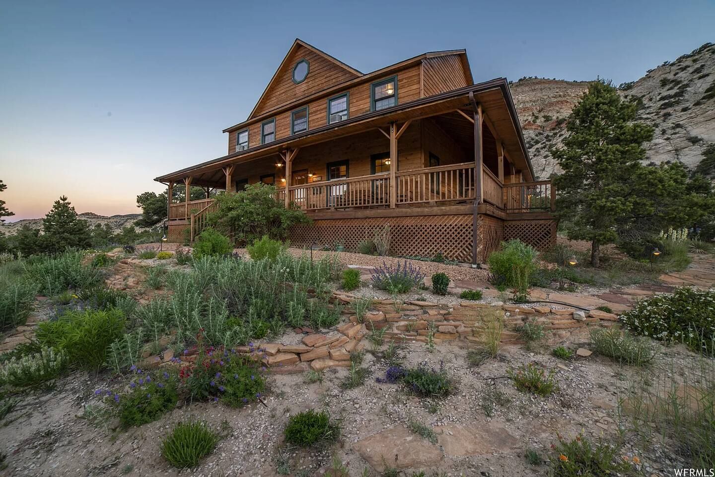 Wooden house with porch on a hillside at dusk.
