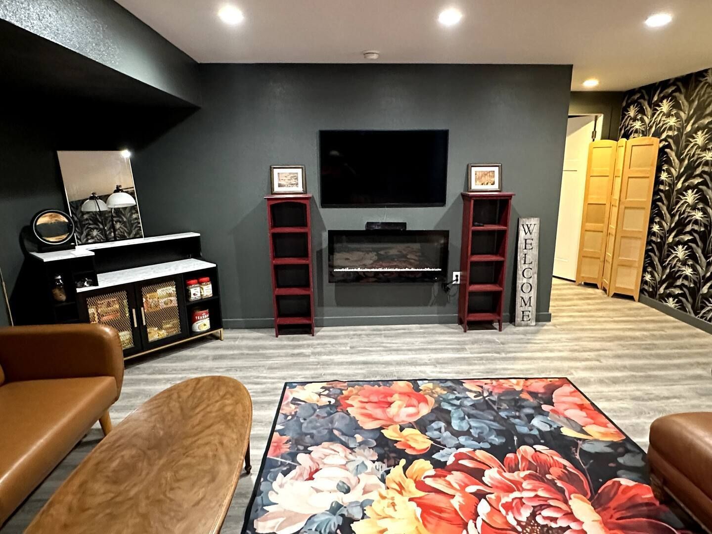 Living room with TV, fireplace, red speaker columns, and floral rug.