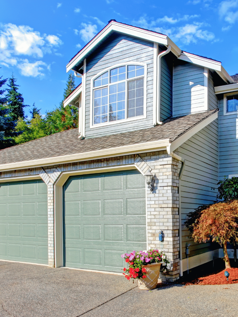 A large house with two garage doors and a large window.