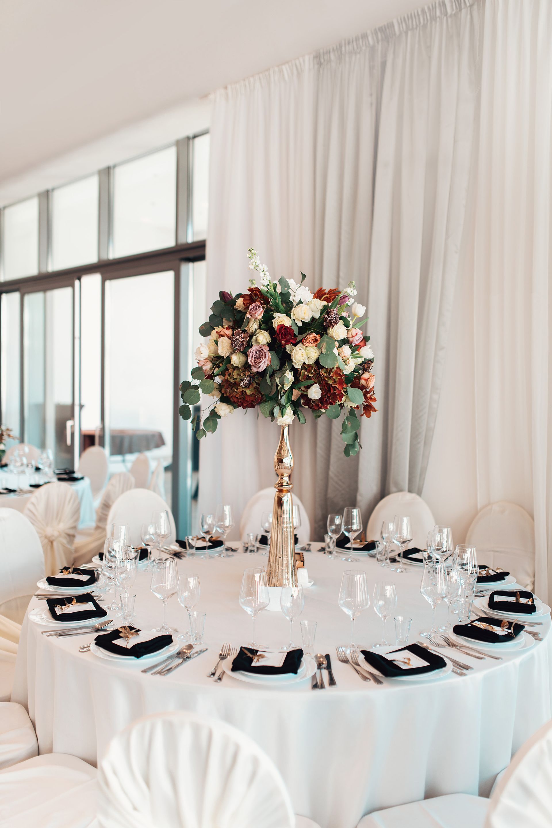 Una mesa preparada para una recepción de boda con un jarrón de flores encima.