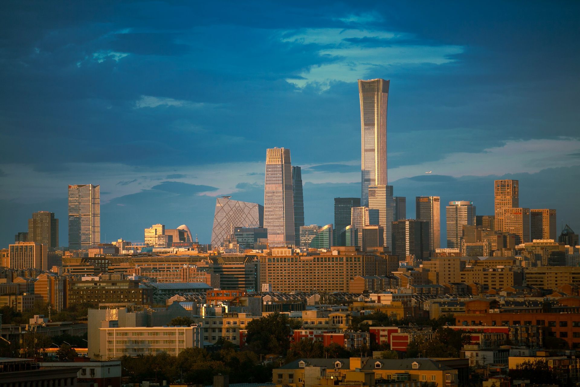City skyline at sunset with tall buildings against a blue and gold sky.