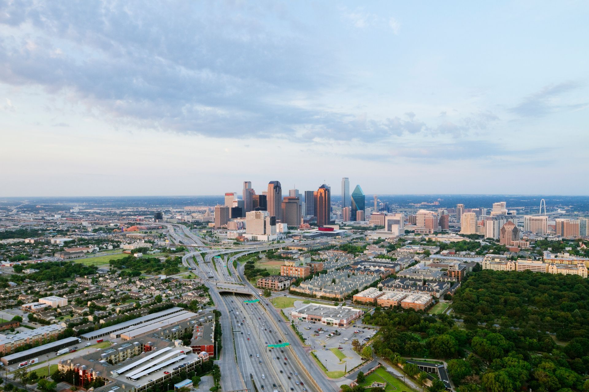 Aerial view of Houston, Texas, with downtown skyscrapers and highways under a partly cloudy sky.