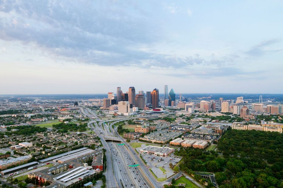 Aerial view of Houston, Texas, with downtown skyscrapers and highways under a partly cloudy sky.