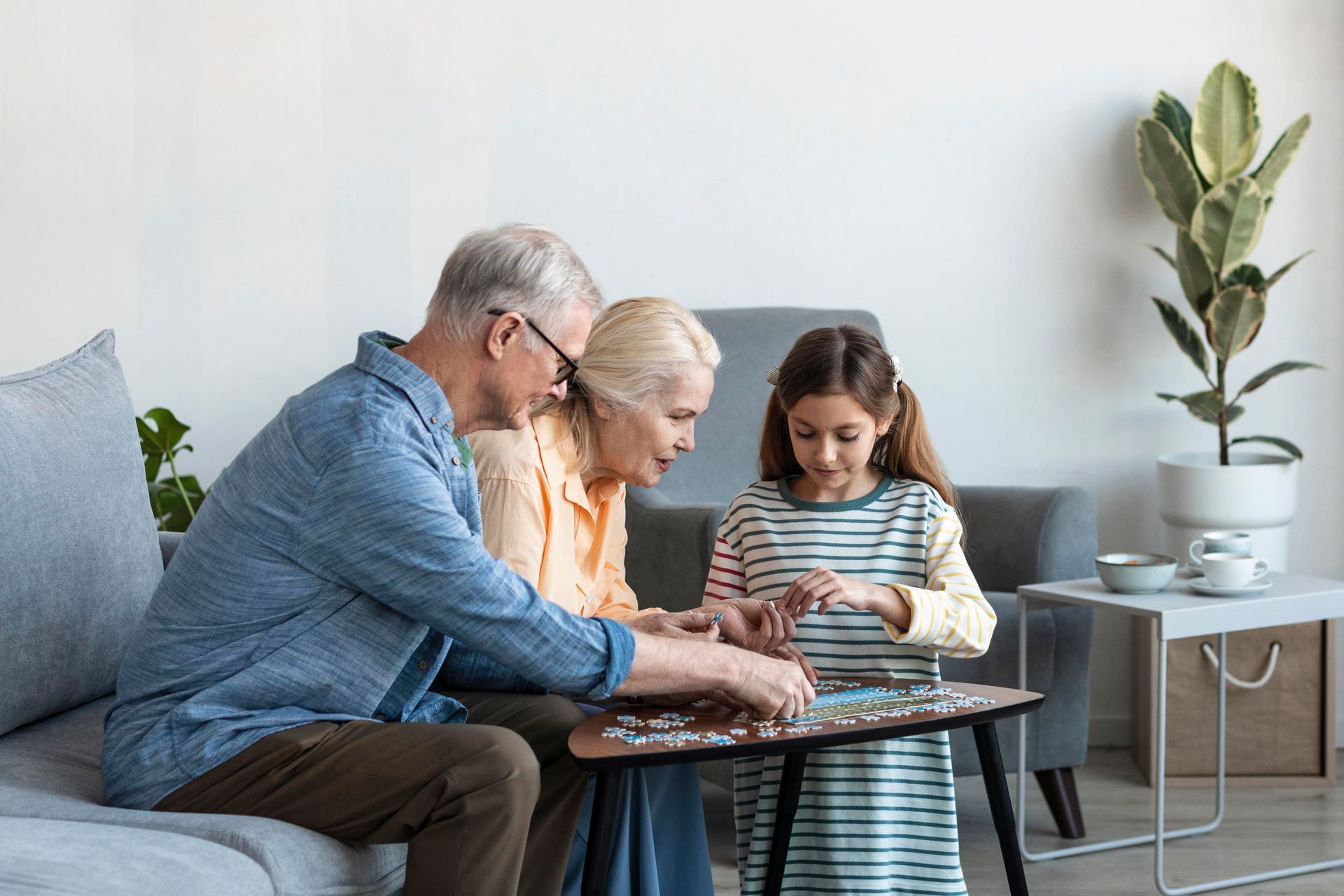 Grandparents and child working on a puzzle in a living room.