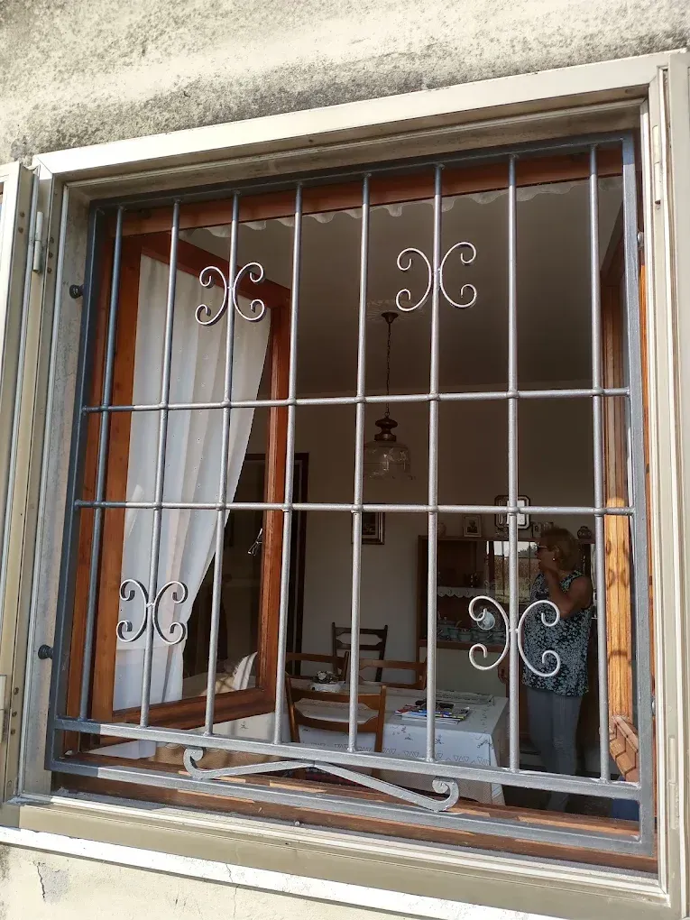 Finestra con sbarre di sicurezza, che mostra l'interno di una stanza con mobili e una persona.