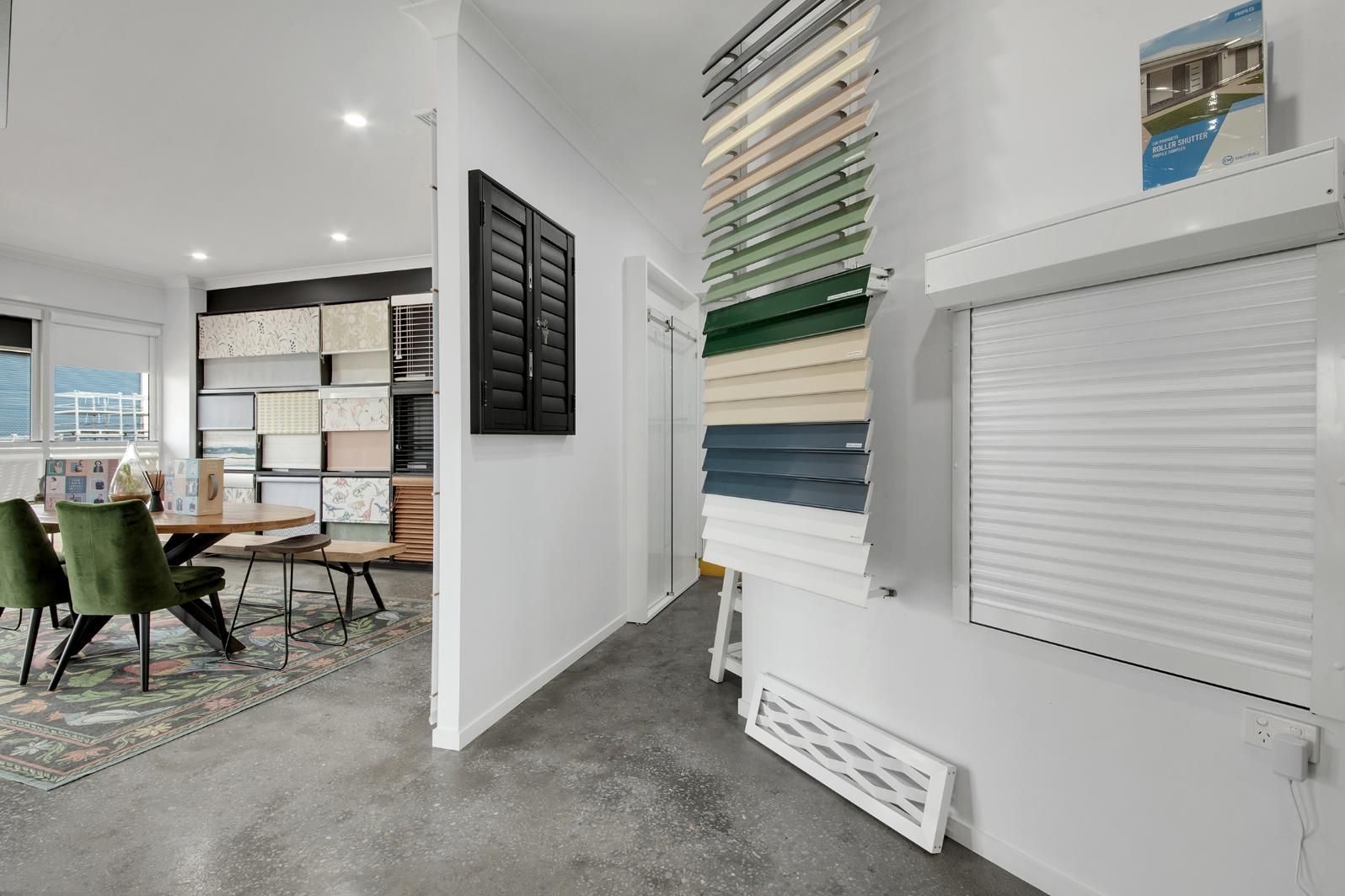 A Room With A Table And Chairs In It And A Display Of Shutters On The Wall — Wares Blinds, Screens & Awnings In Gladstone Central, QLD