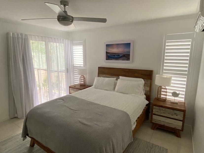 A Bedroom With A Bed , Nightstand , Ceiling Fan And Shutters — Wares Blinds, Screens & Awnings In Gladstone Central, QLD