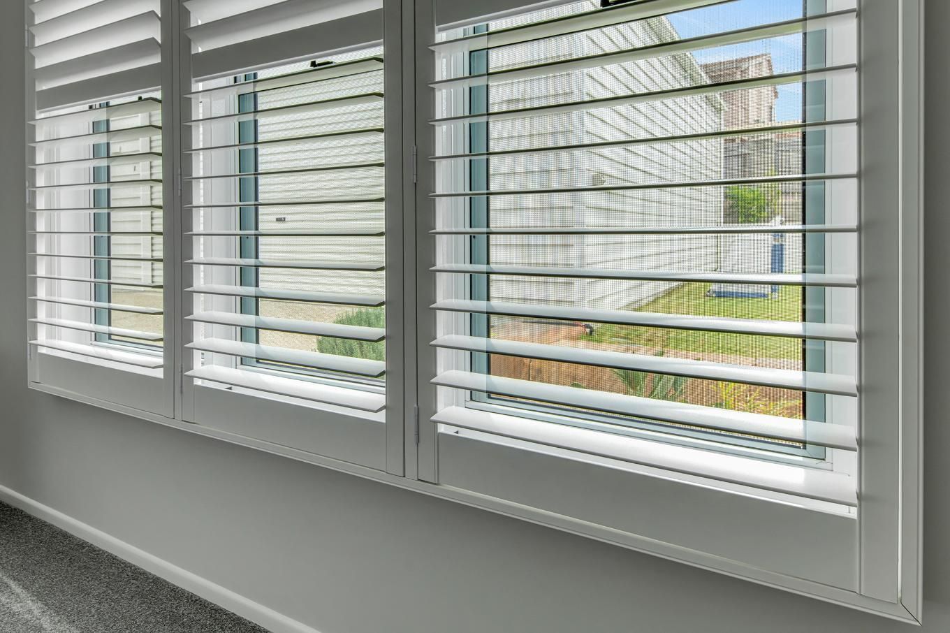 A Close Up Of A Window With White Shutters On It — Wares Blinds, Screens & Awnings In Gladstone Central, QLD