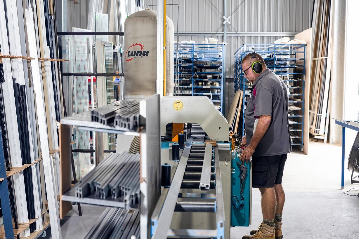 A Man Is Working On A Machine In A Factory — Wares Blinds, Screens & Awnings In Gladstone Central, QLD