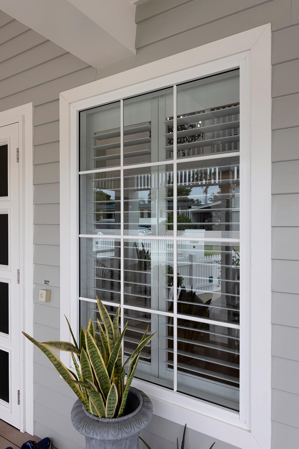 A Potted Plant Is Sitting In Front Of A Window On The Side Of A House — Wares Blinds, Screens & Awnings In Gladstone Central, QLD