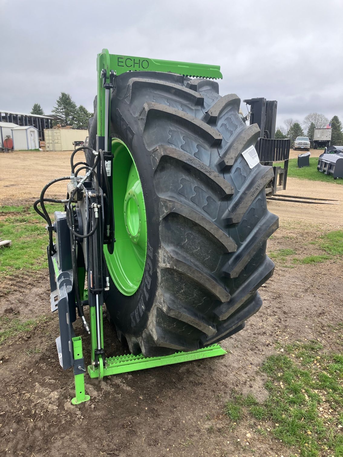 ECHO tire service bundle lifting large tractor tire showing skid steer handler and safe tire handling setup